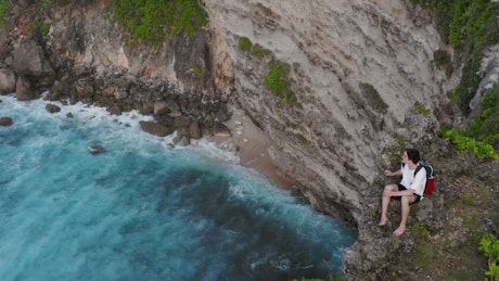 Young wanderlust sees the ocean from a cliff.