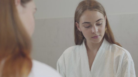 Young woman applies acne cream to face.