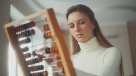 Young woman calculating with a wooden abacus.