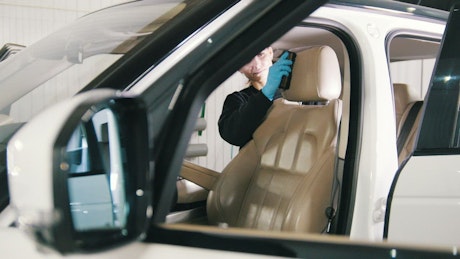 Young woman cleaning the interior of a luxury car