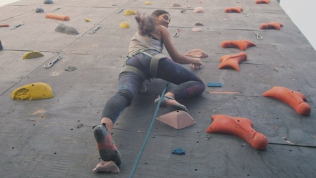 Young woman climbing a large mountaineering wall.