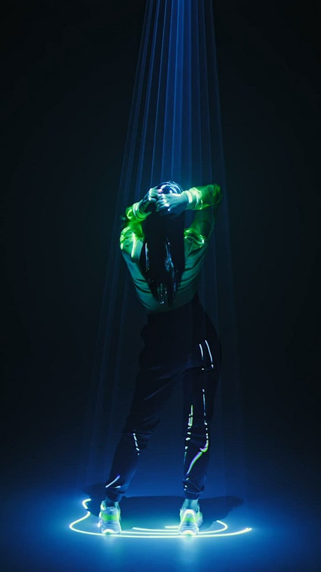 Young woman dances slowly beneath neon lights.