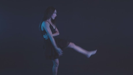 Young woman dancing contemporary dance in the dark.