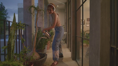 Young woman dancing while watering her plants.