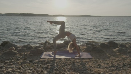 Young woman doing yoga at a sunset on a beach.