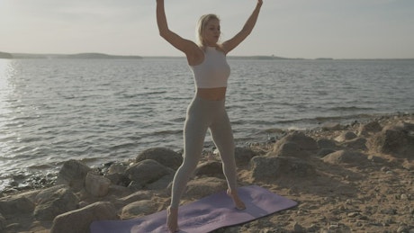 Young woman doing yoga near to the beach.