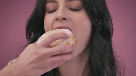 Young woman giving a big bite a donut.