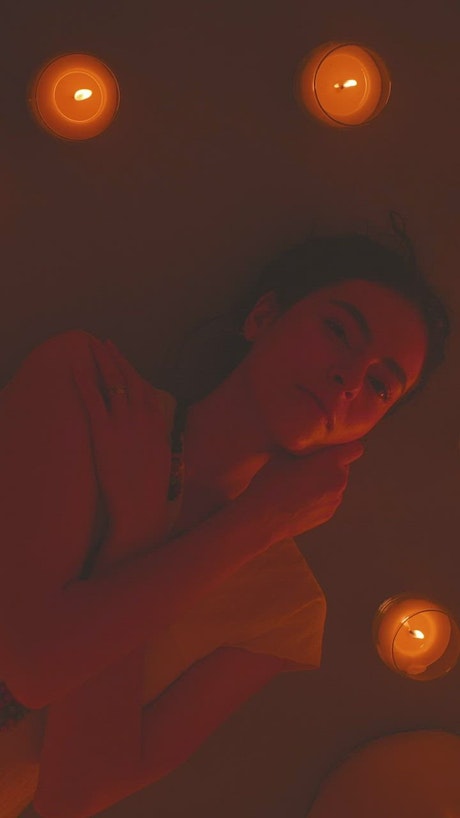 Young woman lying on the floor surrounded by candles