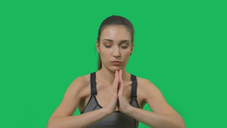 Young woman meditating with a green screen.