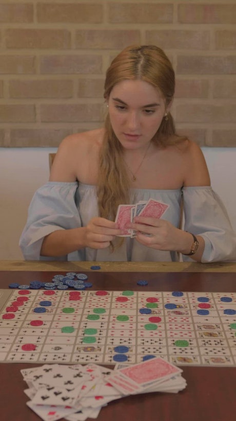 Young woman playing a board game with cards.