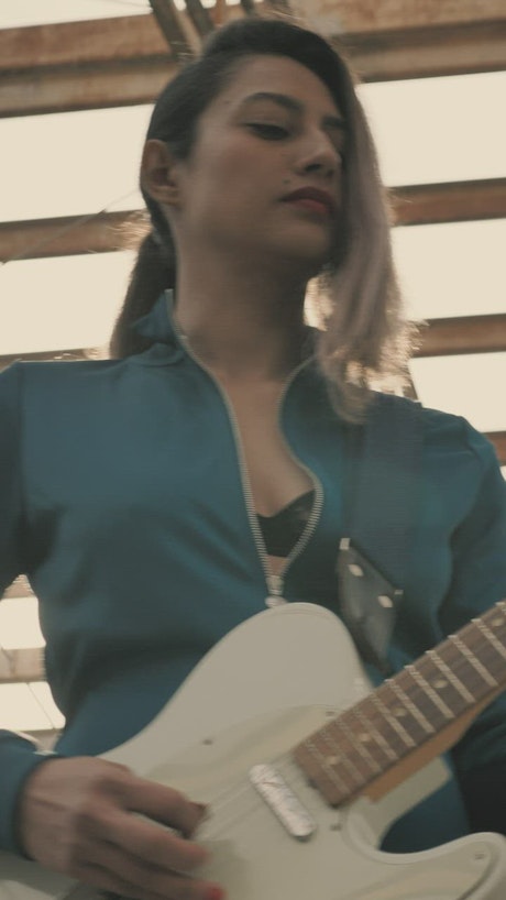 Young woman playing a white electric guitar.