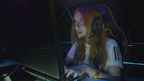 Young woman playing in front of a gamer computer.