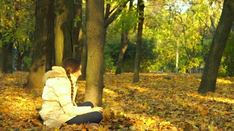 Young woman playing with autumn leaves.