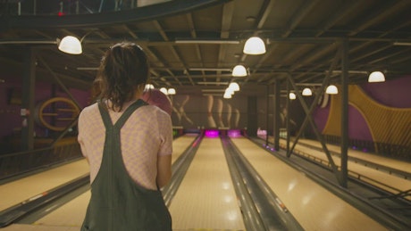 Young woman preparing a shot in the bowling ball lane.