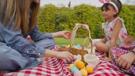 Young woman separating easter eggs with two little girls.