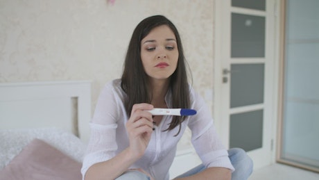 Young woman shocked with her pregnancy test.