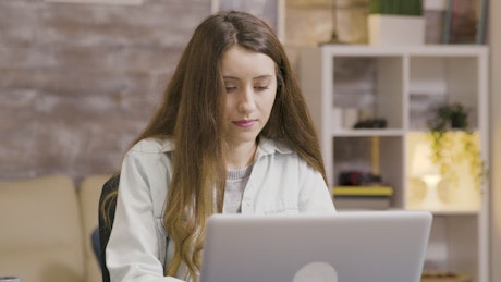 Young woman sips coffee while working from home