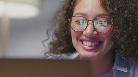 Young woman smiling and waving in greeting to people on a live webinar.