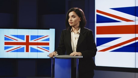 Young woman speaking with UK flag behind her