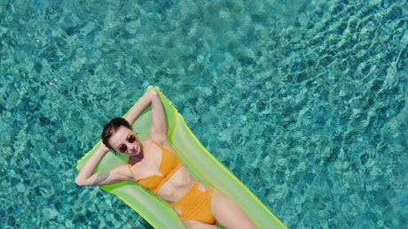 Young woman sunbathing on a inflatable pool bed.
