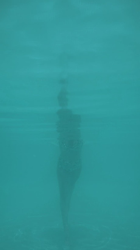 Young woman swimming underwater in a pool.