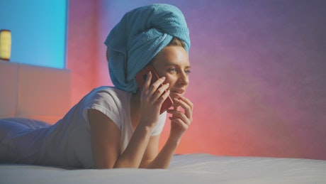 Young woman talking on cellphone before go to bed.