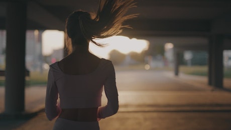 Young woman training in a beautiful sunset at a city.