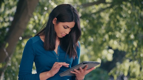 Young woman under a tree using a digital tablet.