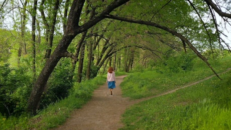 Young woman walking on forest path.