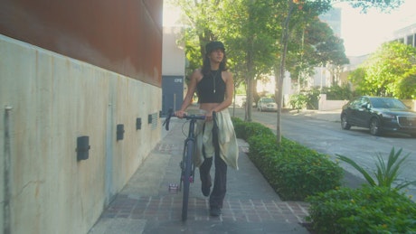 Young woman walking with her bicycle.