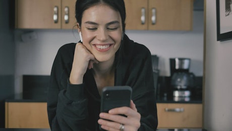 Young woman waving at her cell phone on a video call.