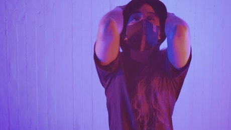 Young woman with a face mask dancing facing the shot.