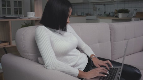 Young woman with laptop working in the couch