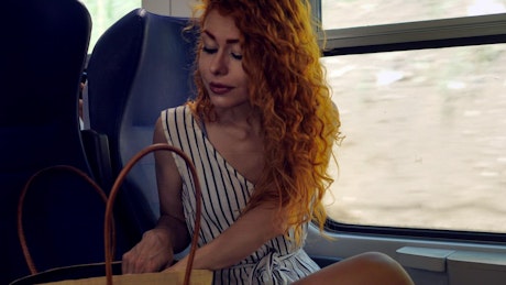 Young woman with red hair relaxing on moving train.