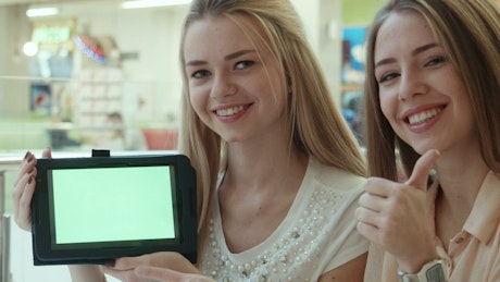 Young women showing a tablet with a green screen